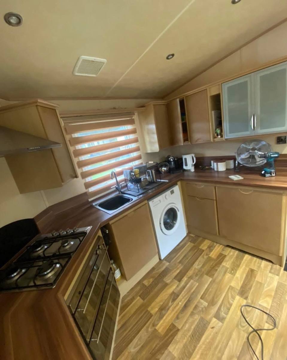 U-shaped caravan kitchen with maple-effect units, before