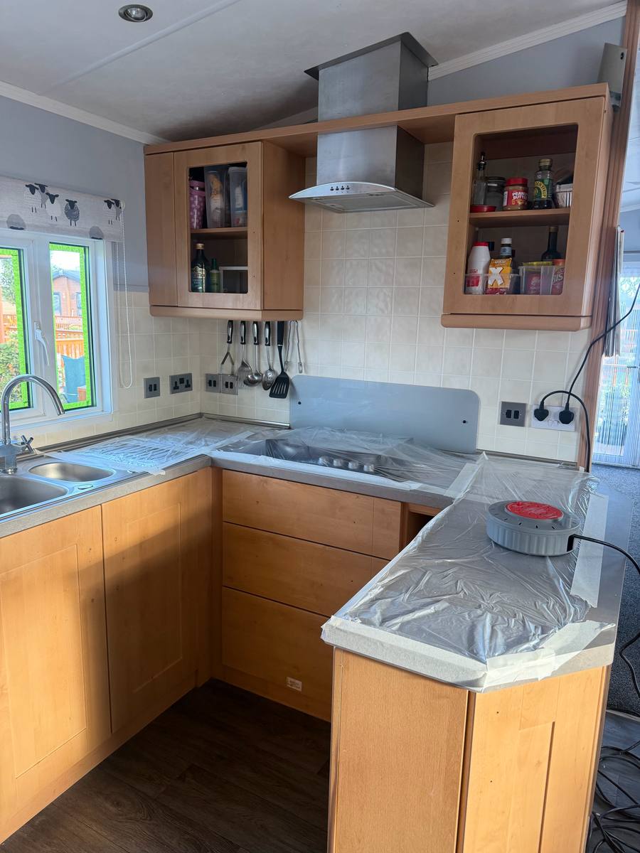 Maple-effect caravan kitchen with the worktop covered in plastic sheeting, before