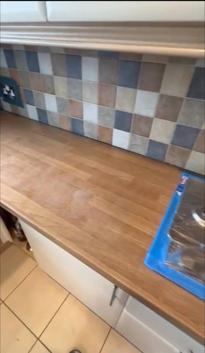 Multicoloured wall tiles and a wood-effect worktop, before