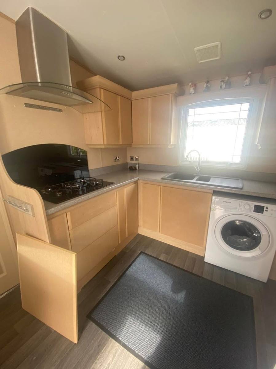 Maple-effect corner kitchen next to a washing machine, before