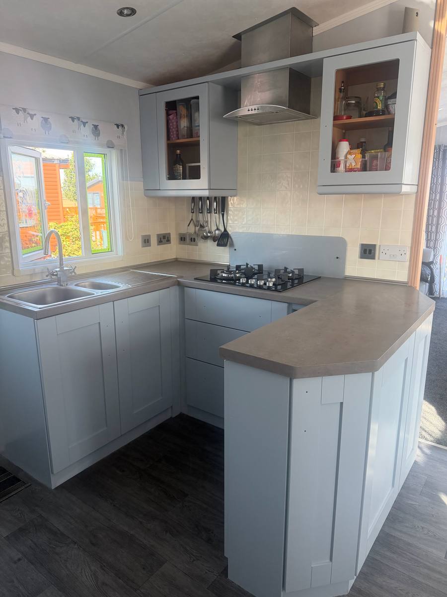 The same kitchen with shaker doors painted pale grey-blue, worktop still under protection