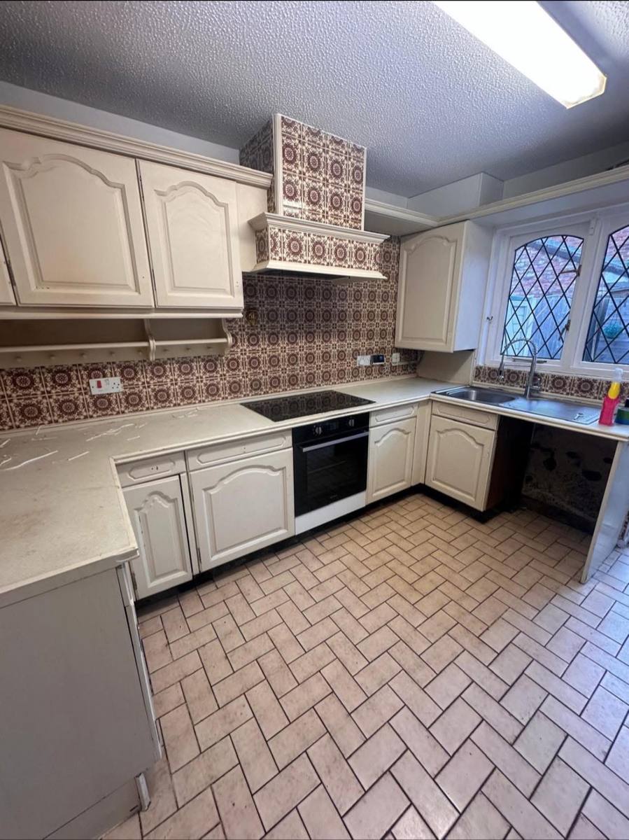 Dated caravan kitchen with old wood-effect units, worktops and tiles, before
