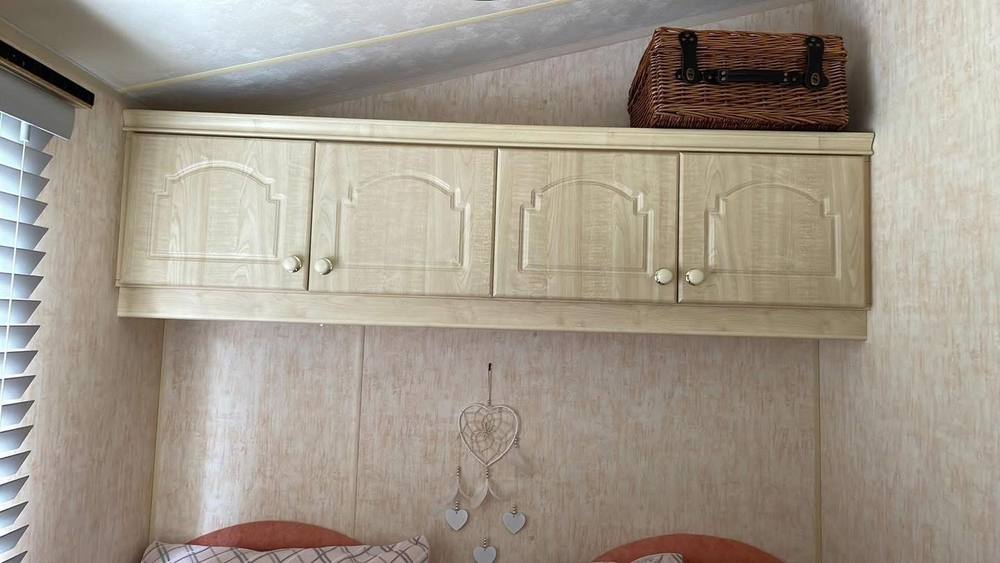 Oak-effect over-bed cupboards in a caravan bedroom, before