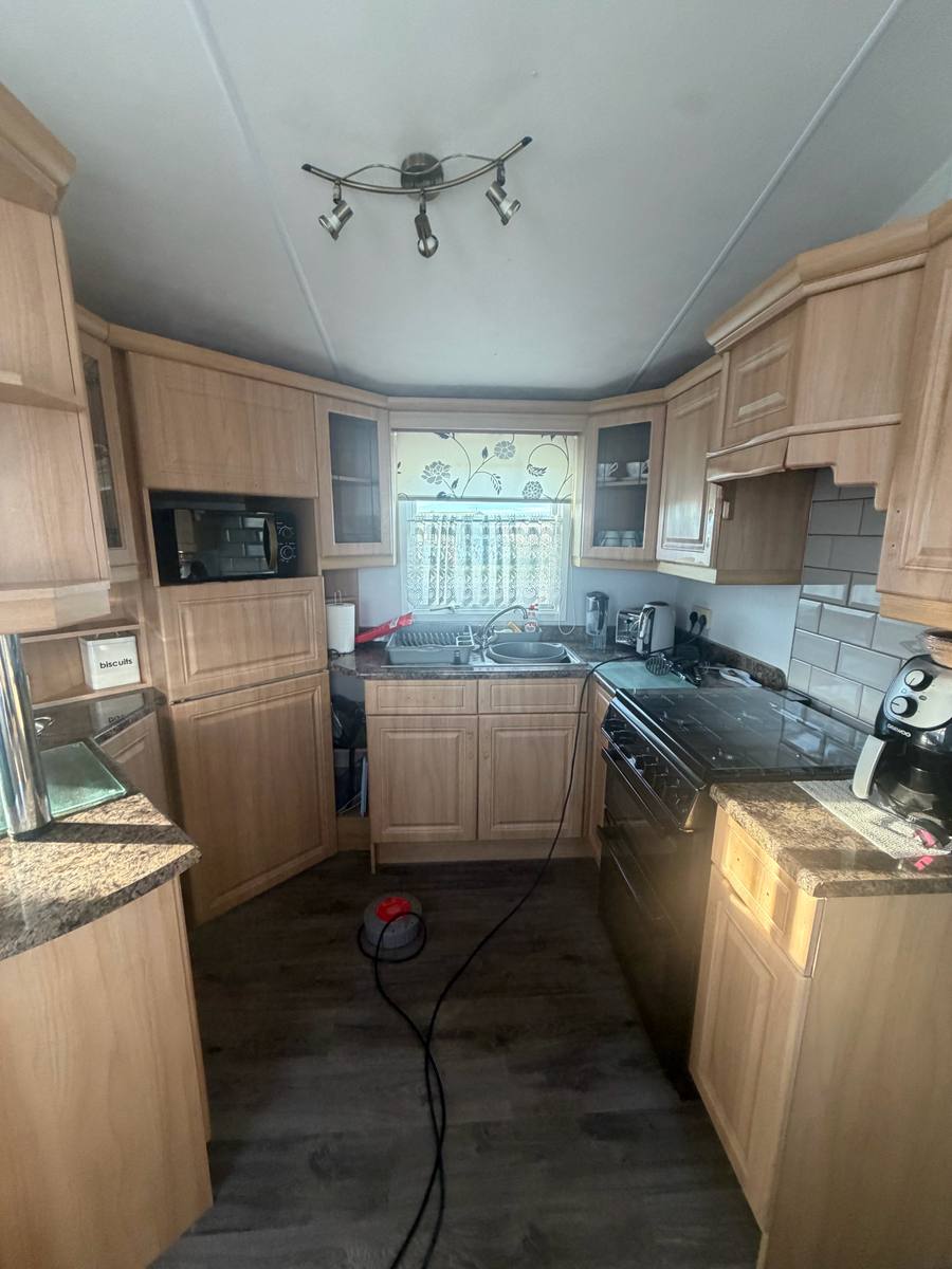 U-shaped caravan kitchen with wood-effect units, before